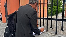 Martin Stropnický podepisuje ped budovou soudu na zídce u plotu Justiního...