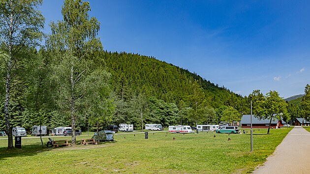 Místa pro karavany i stany, okolo kopce a hřebeny Krkonoš. To je Base Kemp Medvědín.