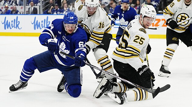 tonk Toronto Maple Leafs David Kmpf bojuje o puk s Pavlem Zachou (uprosted) a Brandonem Carlem z Boston Bruins.