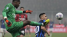 Branká AC Milán Mike Maignan vykopává, otravuje ho Lautaro Martínez z Interu.