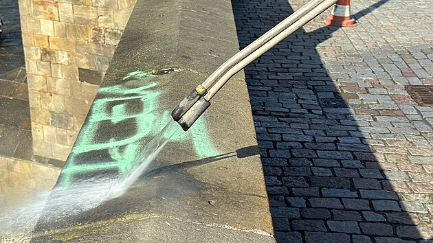 Na Karlově mostě se objevil zeleně nasprejovaný nápis. Pražské služby se ho nyní pokouší odstranit. (20. září 2024)