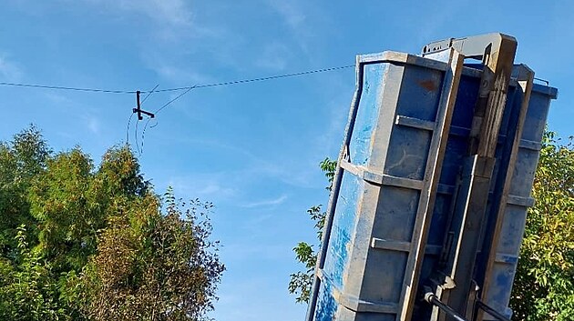 Korba nahoře strhla elektrické vedení. Auto se stalo součástí elektrického obvodu, řidič zůstal uvězněný v kabině.