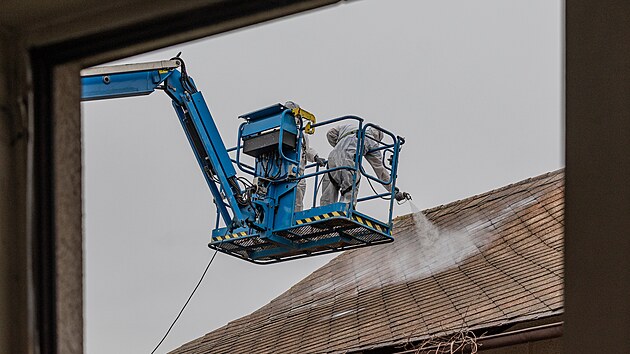 Technici v ochranných oblecích demontují azbestovou krytinu před demolicí domů, které ve Všestarech na Hradecku ustoupí dálnici D35 (7.1.2025).