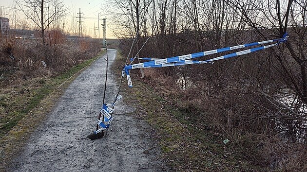 Díra uprostřed cyklostezky v Plzni-Křimicích. Strážníci ji provizorně zabezpečili páskou. (19. ledna 2025)