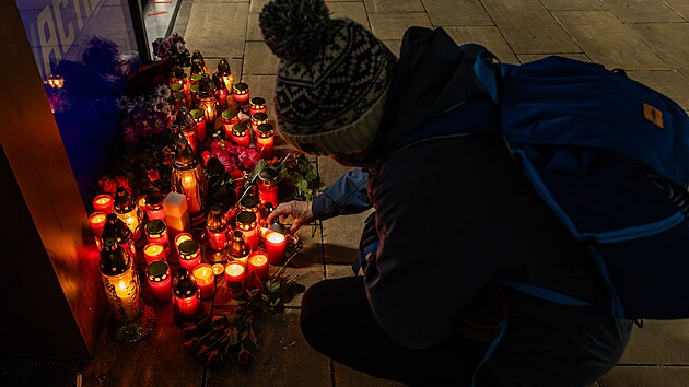 Lidé zapalují svíčky u prodejny v Hradci Králové, kde mladík ubodal dvě prodavačky (20. 2. 2025).