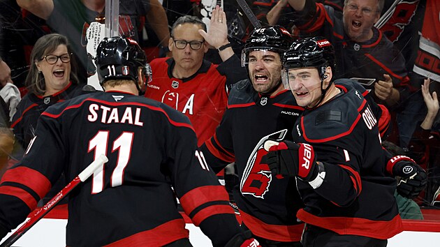 Jordan Martinook, Dmitrij Orlov a Jordan Staal slaví gól Carolina Hurricanes.