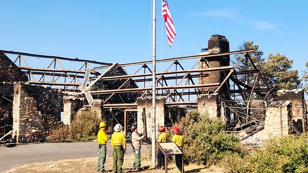 Hasiči uprostřed zničené chaty Grand Canyon Lodge vztyčili americkou vlajku. (19. července 2025)