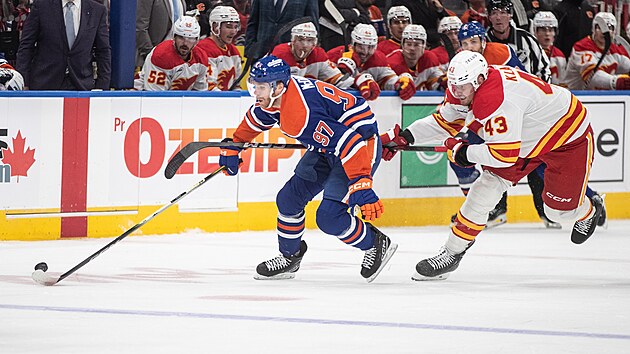 Adam Klapka (43) z Calgary Flames se natahuje, ujíždí mu Connor McDavid (97) z Edmonton Oilers.