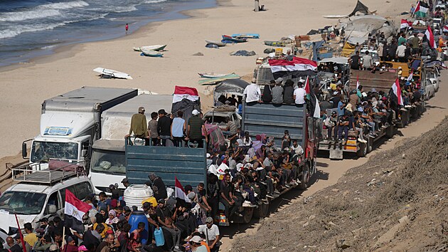 Vysídlení Palestinci jedou na nákladních vozech naložených svými věcmi a mávají egyptskými a palestinskými vlajkami, zatímco cestují po pobřežní silnici poblíž Wadi Gaza ve střední části Pásma Gazy směrem k městu Gaza. (11. října 2025)