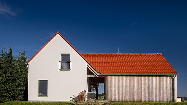Na malé jihočeské vesničce stojí jen pár typických statků. Nová moderní dřevostavba mezi ně svým stylem dokonale zapadá.