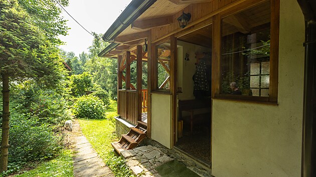 Chatka je obklopena zelení, travou a mnoha keři.