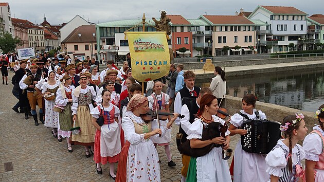 Členové souboru Písečan procházejí po Kamenném mostě v Písku. Průvod souborů je součástí mezinárodního folklorního festivalu.
