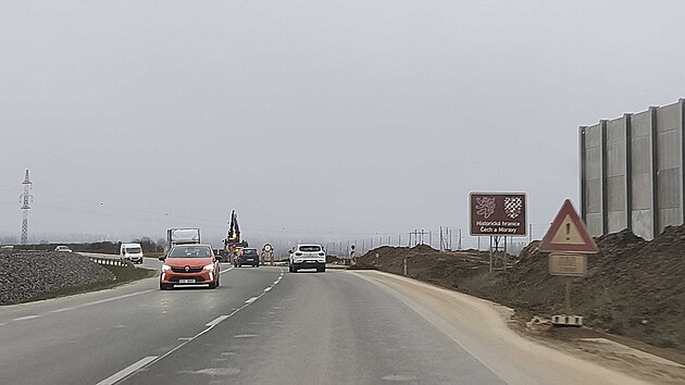 Hnědá cedule s českým lvem a moravskou orlicí na silnici I/35 u rozestavěné dálnice poblíž Opatovce