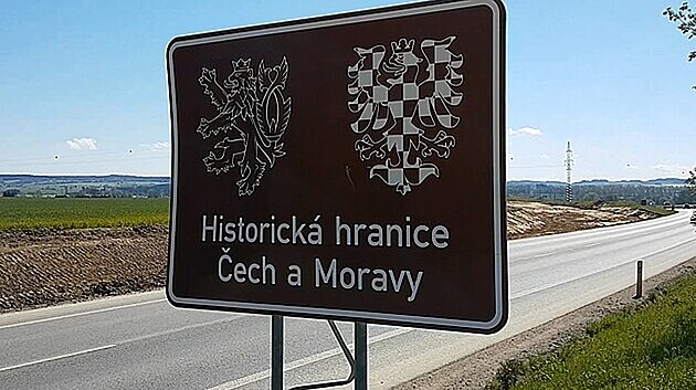 Hnědá cedule s českým lvem a moravskou orlicí na silnici I/35 u rozestavěné dálnice poblíž Opatovce