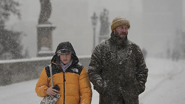 Návštěvníci Karlova mostu v Praze si užívají sněžení. (9. ledna 2026)