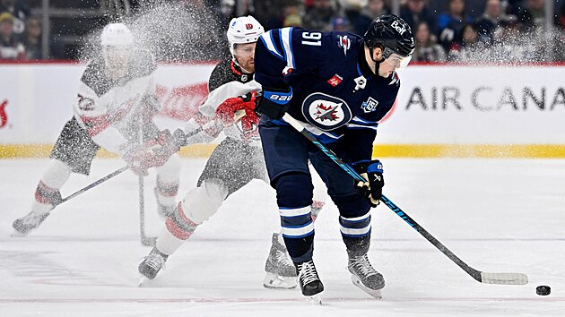 Cole Perfetti z Winnipegu s pukem před Connorem Brownem z New Jersey