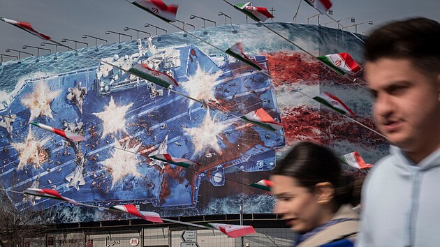 Íránci v Teheránu procházejí kolem státní budovy pokryté protizápadním billboardem, na kterém je obrázek zničené letadlové lodi Abraham Lincoln. (28. ledna 2026)