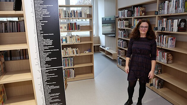 Stejná místnost o rok později. Markéta Beyerová mezi regály s knihami,...
