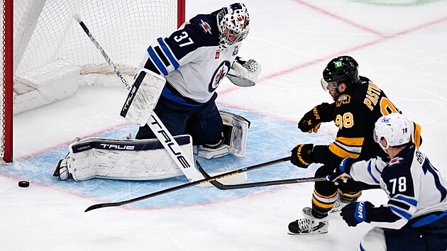 David Pastrňák z Bostonu (v černém) operuje před brankou Winnipegu v utkání NHL.