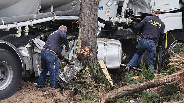 Pracovníci odtahové služby připravují havarovaný kamion u Pávova k vyproštění. Souprava je po nárazu zaklíněná mezi kmeny stromů, což komplikuje celou operaci.