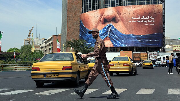 Íránský voják prochází kolem velkého protiamerického billboardu s prezidentem Donaldem Trumpem a motivem Hormuzského průlivu na náměstí v Teheránu. (2. května 2026)