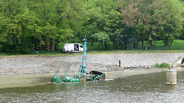 Zat&iacute;mco obsluha s d&aacute;lkov&yacute;m ovl&aacute;d&aacute;n&iacute;m sed&iacute; na břehu, buldozer cestuje po dně Labe a vyv&aacute;ž&iacute; materi&aacute;l na kraj ř&iacute;čn&iacute;ho koryta.