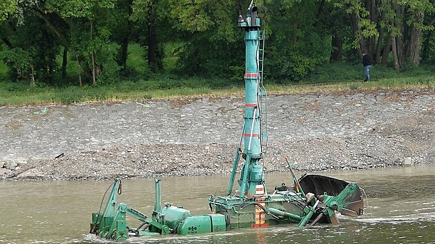 Zat&iacute;mco obsluha s d&aacute;lkov&yacute;m ovl&aacute;d&aacute;n&iacute;m sed&iacute; na břehu, buldozer cestuje po dně Labe a vyv&aacute;ž&iacute; materi&aacute;l na kraj ř&iacute;čn&iacute;ho koryta.