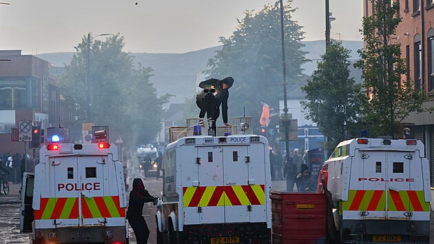 Policejní vozidla čelí útokům demonstrantů během nepokojů v severoirském Belfastu po útoku nožem. (9. června 2026)
