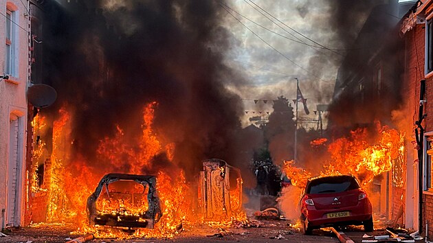 Automobily zapálené demonstranty hoří v ulici Lendrick Street v Belfastu. (9. června 2026)