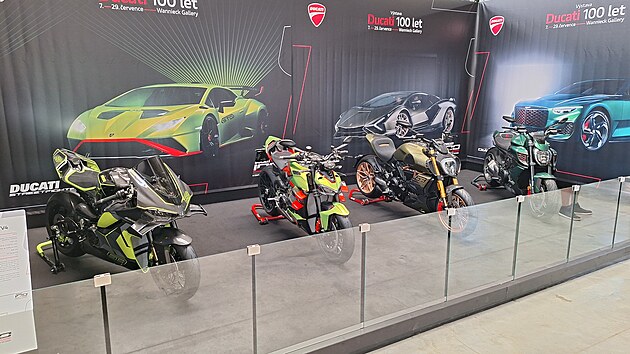 Tradicí továrny Ducati je spolupráce s výrobci ušlechtilých automobilů. Na snímku jsou tři speciální edice Lamborghini, zleva Panigale V4 (2026) ve stylu Revuelta, Streetfighter V4 (2023) inspirovaný Huracánem STO a Diavel 1260 (2021) připomínající Lamborghini Sian. Zcela vpravo je doplňuje jeden z pouhých 550 vyrobených strojů série Ducati Diavel for Bentley (2024), záměrně připomínající exkluzivní kupé Bentley Batur a vynikající kovanými, do titanově šedé barvy zbarvenými ráfky či typickým zeleným lakováním Scarab Green.