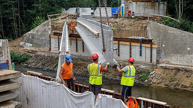 Stavbaři pomocí jeřábu osazují osm železobetonových nosníků. Každý z nich váží 28,5 tuny a měří téměř 30 metrů.