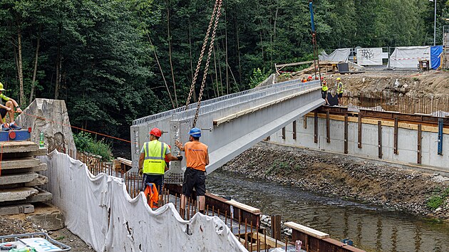 Stavbaři pomocí jeřábu osazují osm železobetonových nosníků. Každý z nich váží 28,5 tuny a měří téměř 30 metrů.
