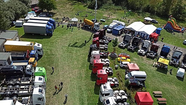 Pohled shora na zaplněný areál kempu v Pávově. Snímek zachycuje precizně srovnané tahače, stany zázemí i proudící návštěvníky.