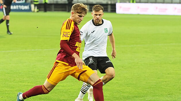 Denis Zamazal z Dukly Praha odkop&aacute;v&aacute; m&iacute;č před karvinsk&yacute;m Radimem Breitem.