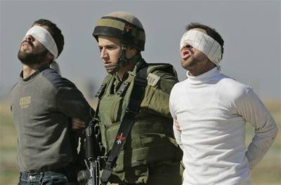 Izraelský voják vede palestinské bojovníky zajaté pi protiteroristické operaci v pásmu Gazy. 