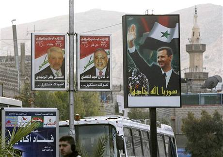 Prezident Asad (vpravo) na billboardu v Damaku. Vedle jsou irátí kandidáti do nedávných voleb. V Sýrii je 1,5 milionu uprchlík z Iráku. 