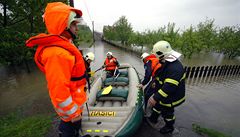 Dobrovolní hasii pomáhají s evakuací obyvatel zatopených dom.