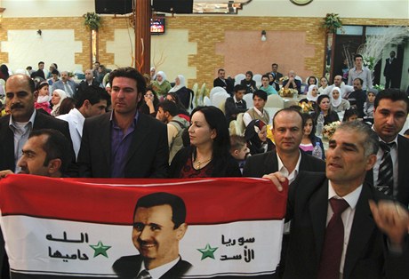 Kurdové nesou vlajku Sýrie s portrétem prezidenta Baára Asada.  