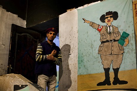 Rebel v Benghází ped portrétem, který Kaddáfího zobrazuje jako Hitlera