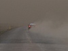 Auto projídí na dálnici u msta Kirkjubaejarklaustur, okolí je pokryté popelem a prachem