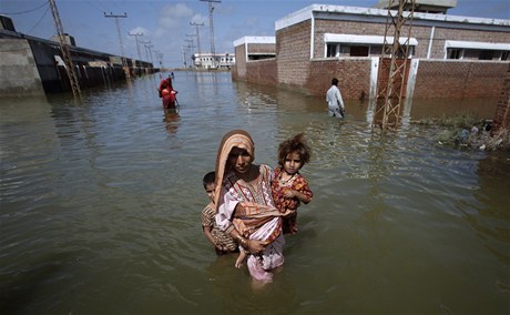 Povodn v Pákistánu - ena se snaí pemístit sebe a své dti nkam na vyí místo.