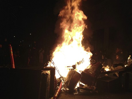 V noci se protest v centru Oaklandu vystupoval. Uprosted jedné z ulic zaloili demonstranti hranici z odpadkových ko, kterou zapálili.