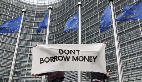 Studenti drí tansparent proti dalímu zadluování.  Za jejich zády se odehrává pelomový summit EU.