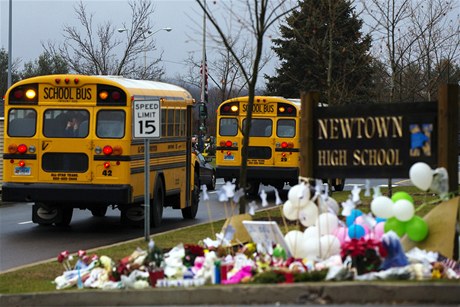 kolní autobusy v Newtownu projídjí kolem provizorního památníku obtí stelby z prosince 2012.