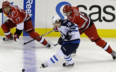Hokejisté Carolina Hurricanes' Joe Corvo (77) a Jií Tlustý (19) brání hráe Winnipegu Jets' Bryan Little (18).