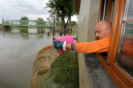 Stanislav Ullman vylévá bahnitou vodu oknem do rozvodnné Blanice.