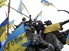 Demonstranti vylezli na sochu a mávají ukrajinskými vlajkami. 