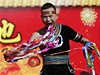 Novoroní slavnosti v Pekingu: kejklí si vytahuje z úst barevné stuhy.