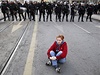 Protivldn demonstrantka sed na ulici Sarajeva, v pozad policejn kordon.