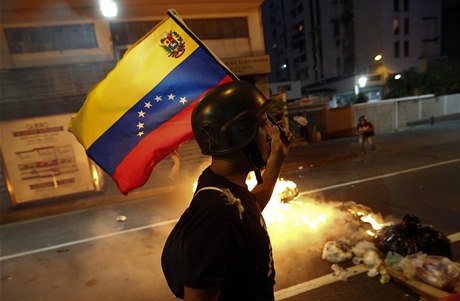 Opoziní demonstrant nese venezuelskou vlajku